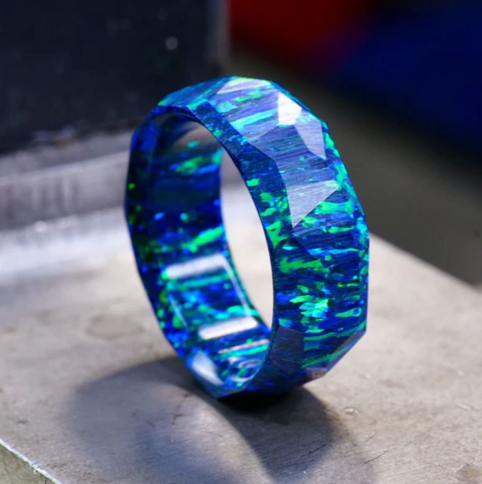 A close up of one of Patrick Adair's men's unique wedding rings with very bold and almost glowing blue ring with green flecks inside