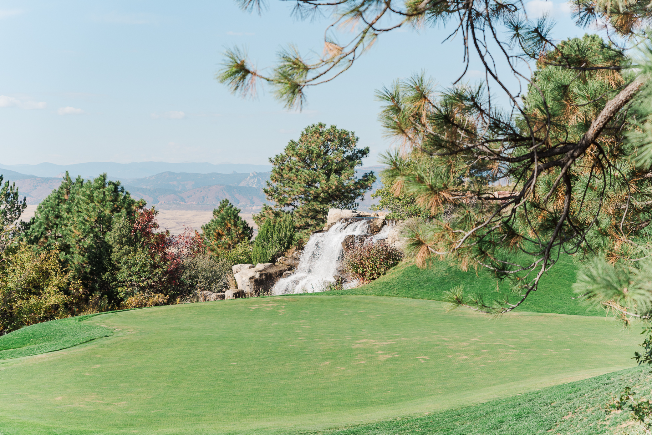 A water fall on one of the holes at Sanctuary golf course wedding venue with a view of the mountains in the background