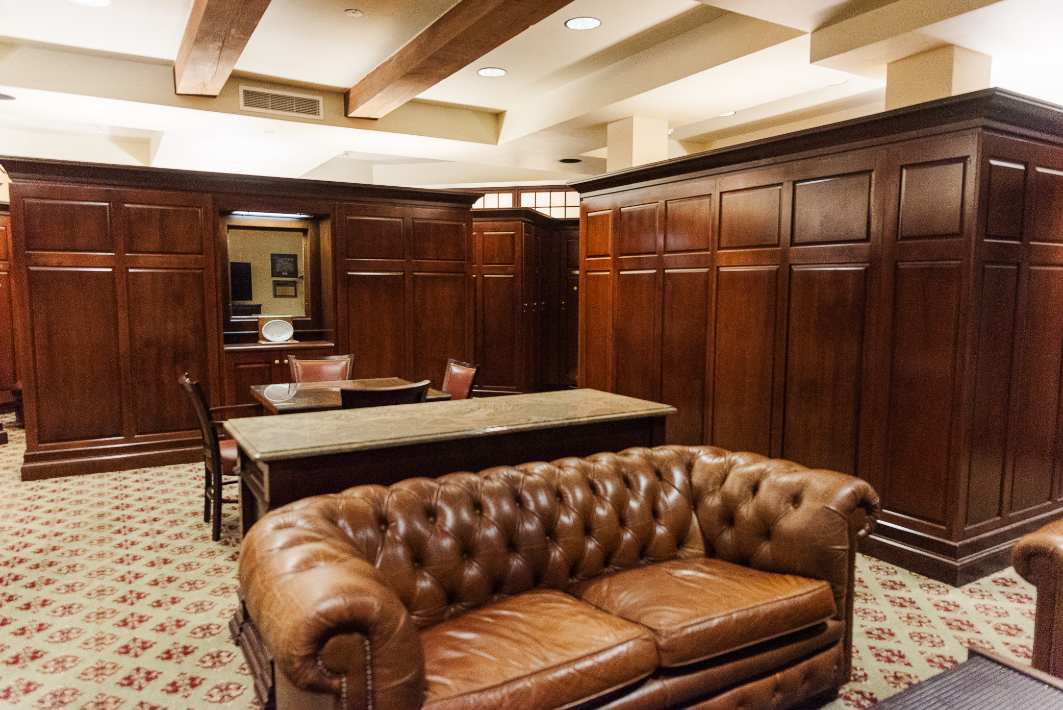 The groom's room for a sanctuary golf course wedding with a brown leather couch, a brown table with brown leather chairs and maple lockers