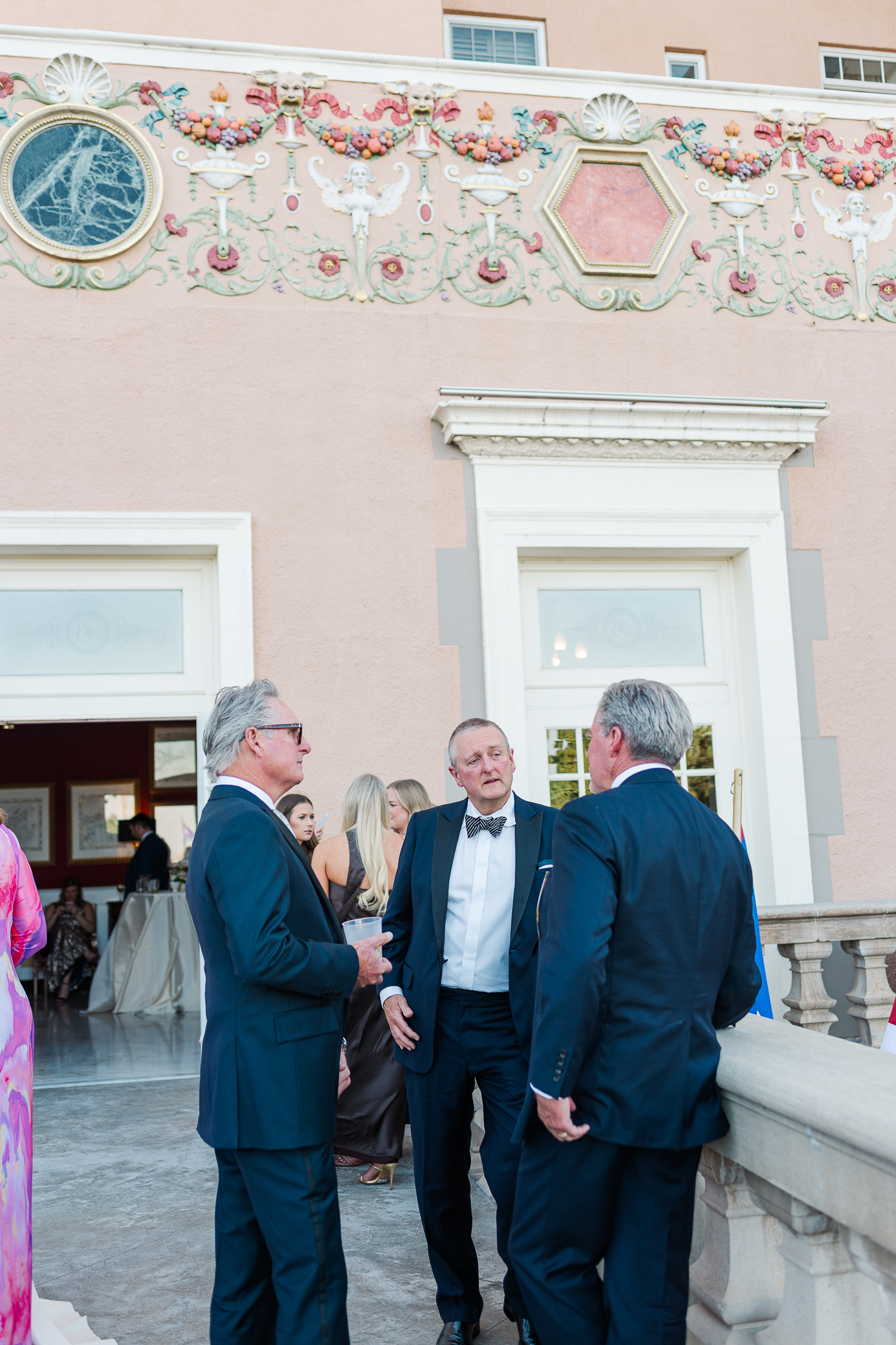 A group of men chat during cocktail hour on the terrace of a hotel.