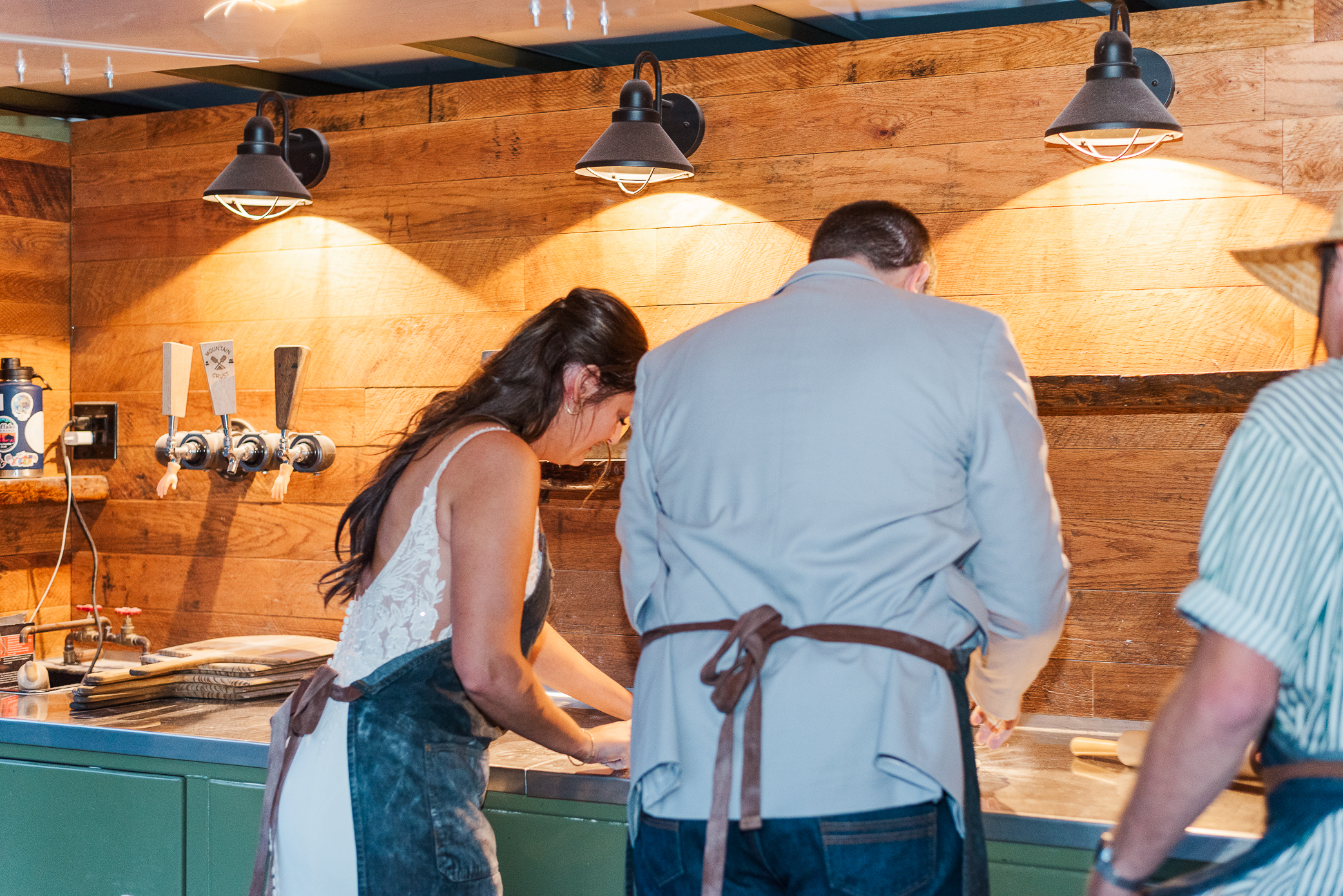 A bride and groom work on rolling out pizza dough at Mountain crust event venue for their guests