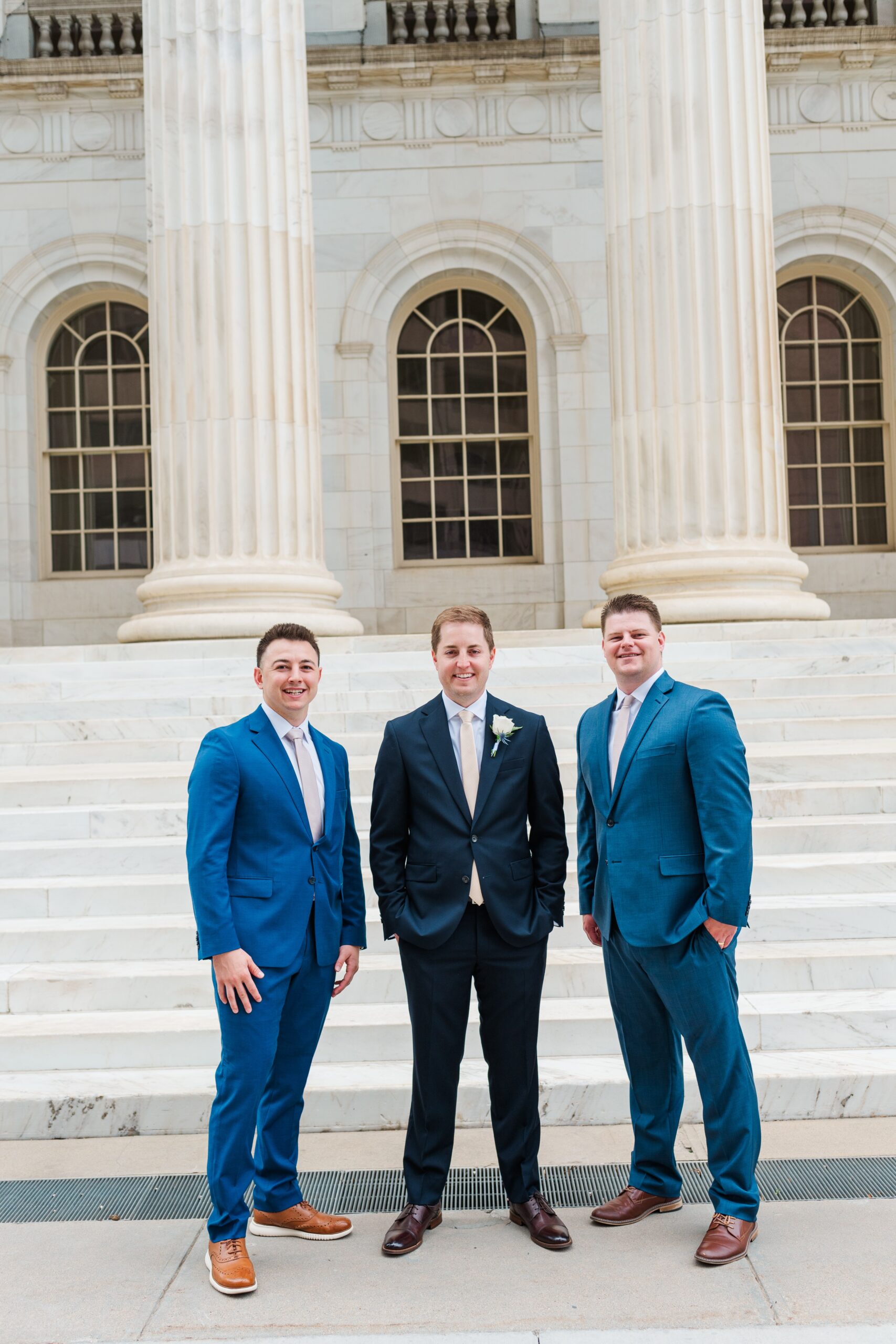 A groom stands with his groomsmen smiling for the camera for his Byron White Courthouse wedding
