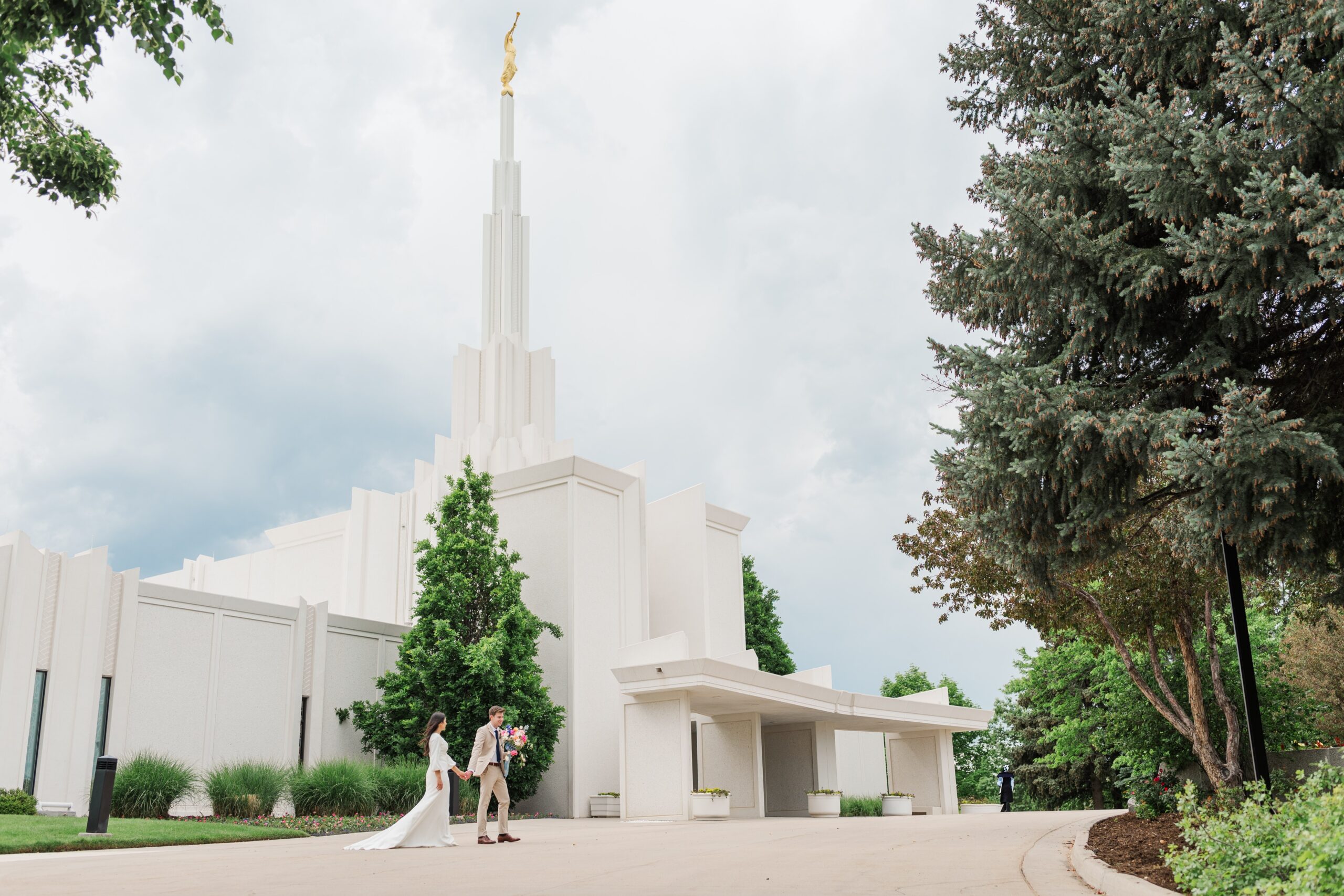 A couple on their wedding day walks across the street from the Denver LDS temple wedding that they just had on a beautiful summer day