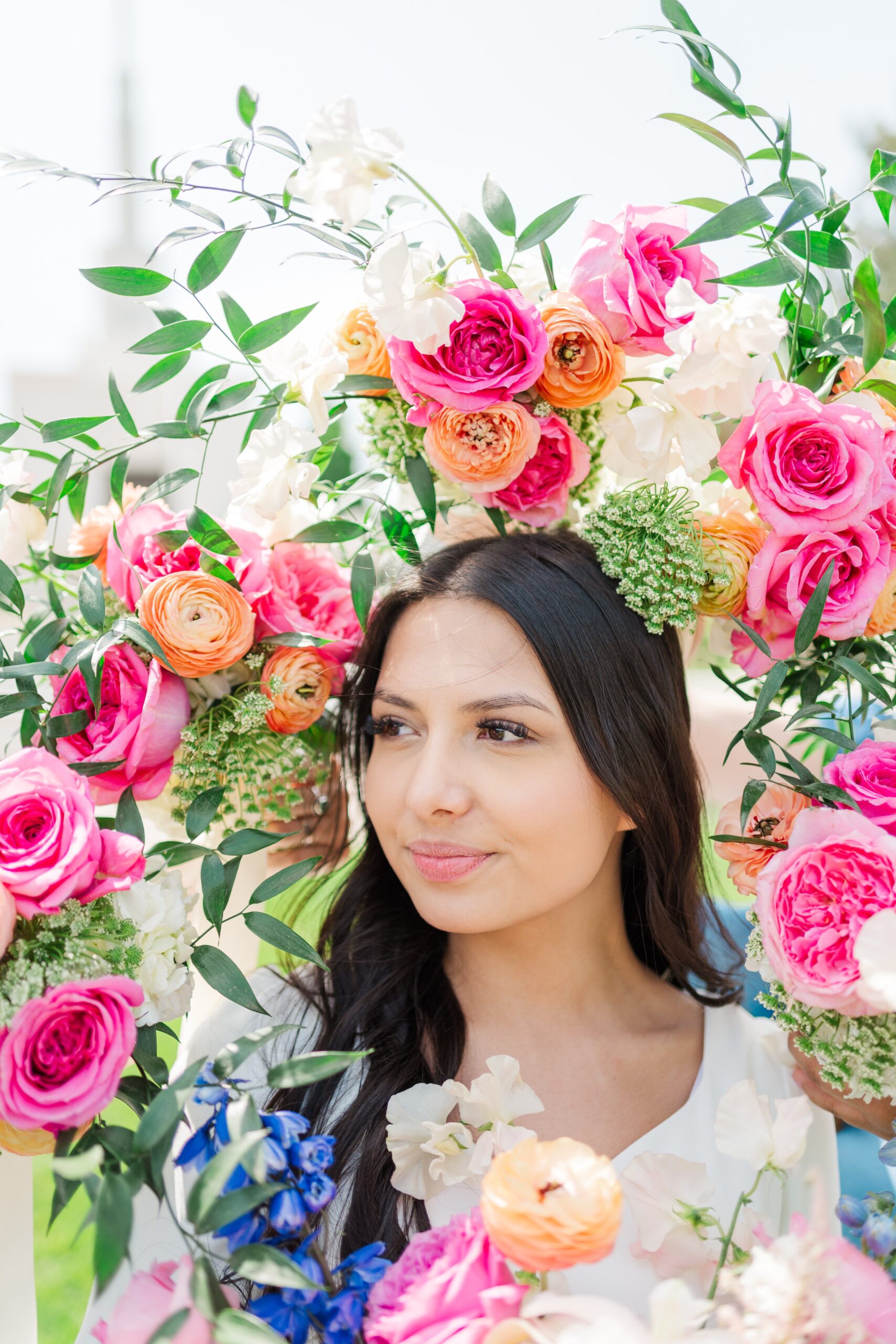 A bride is surrounded by colorful pink, orange, and green flowers like a flower crown at her Denver LDS Temple wedding